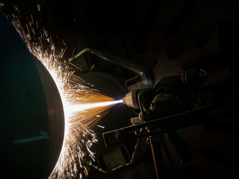 Projection thermique sur une surface métallique rotative avec de fortes étincelles.