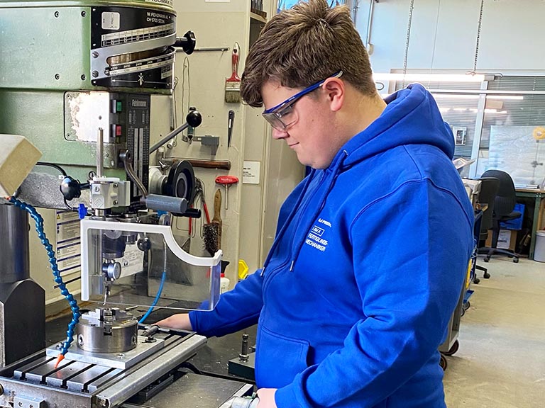 Bild eines Auszubildenden in der mechanischen Werkstatt Luca an seinem Arbeitsplatz in der mechanischen Werkstatt als Auszubildende Fertigungsmechaniker